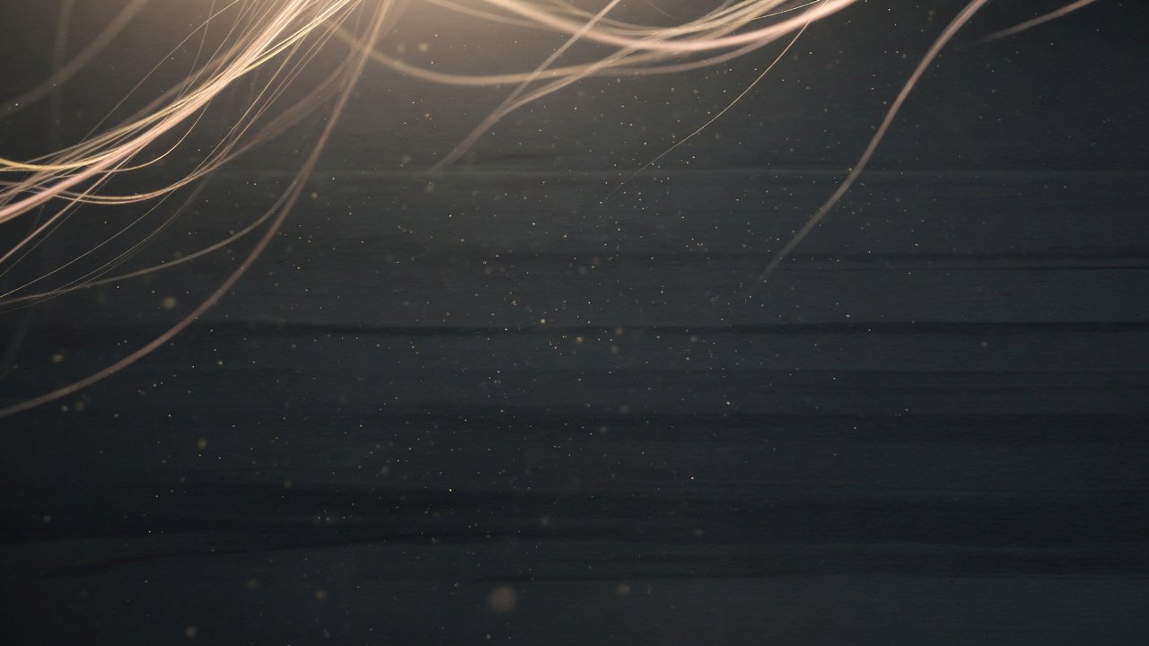 Abstract soft golden light threads on deep charcoal suggesting calm clarity